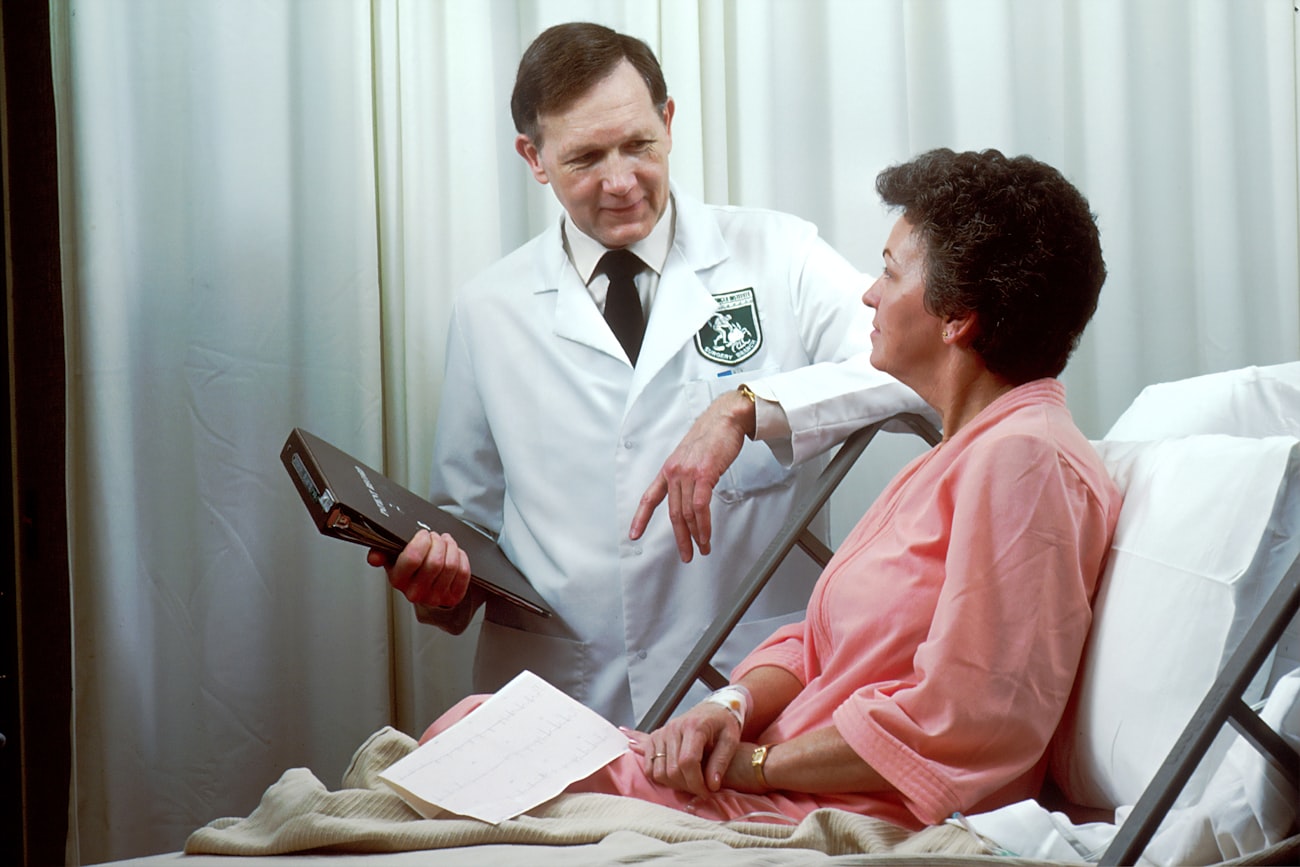 A clinician talking with a smiling patient during a bedside visit